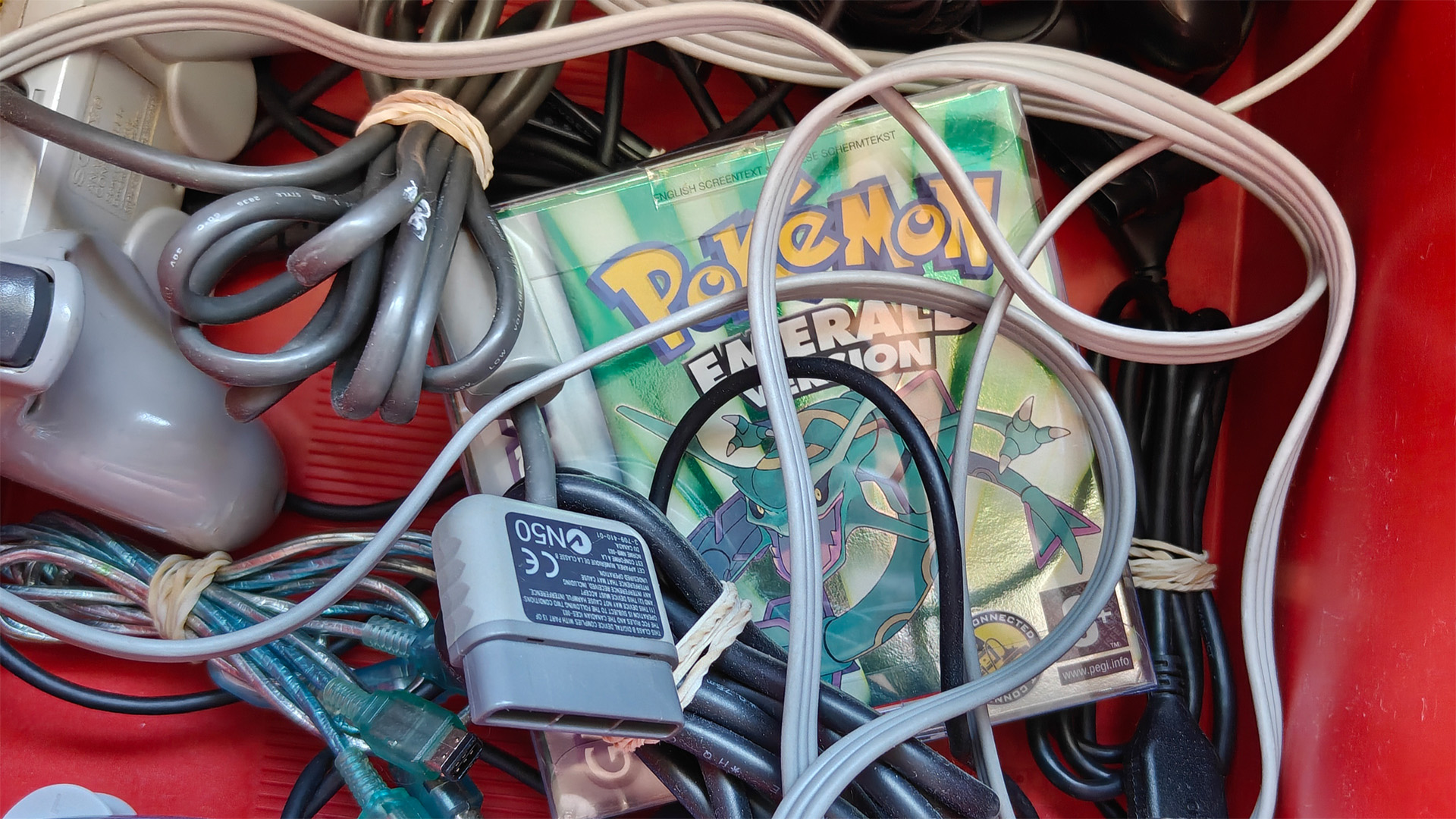 Pokémon Emerald, halb vergraben in einer Kiste voller loser Kabel und Controller.